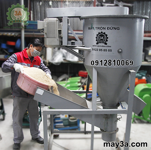 Kỹ thuật viên cho cám vào cửa nạp nguyên liệu của Máy trộn cám 3A5,5Kw